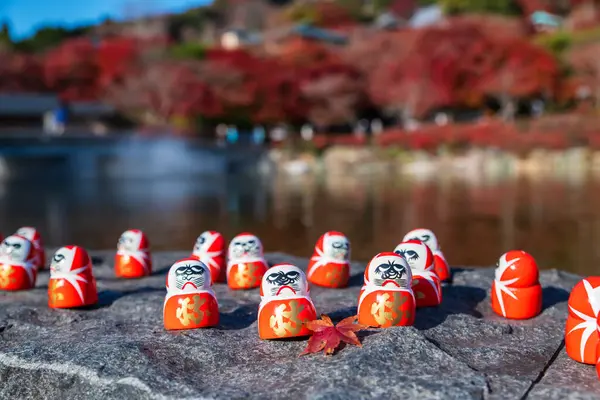 Japonya 'nın Minoh, Osaka kentindeki Katsuo-ji Tapınağı' nın sonbaharında kırmızı akçaağaç yapraklı Daruma bebekleri. Sonbaharda Kansai 'yi görmek için ünlü bir seyahat yeri. Zafer tapınağı.