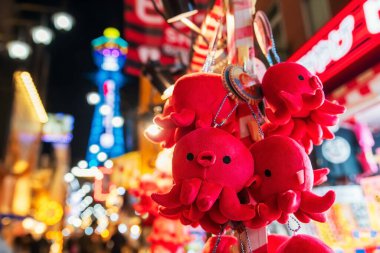 Japonya, Osaka 'daki Tsutenkaku Kulesi' nin yanındaki Shinsekai Osakas Yeni Dünya Caddesi 'ndeki dükkandan pembe ahtapot hatırası. Işıklandırılmış süslü reklam panosu ya da tabelası olan ünlü seyahat yeri.