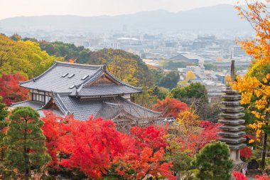 Japonya 'nın Kyoto kentindeki Kiyomizu-dera tapınağının renkli sonbahar yapraklı havadan görünüşü. Tapınağın canlı kırmızı ve turuncu pagodası rengarenk yapraklarla öne çıkıyor. Manzaralı güzelliği arttırıyor..
