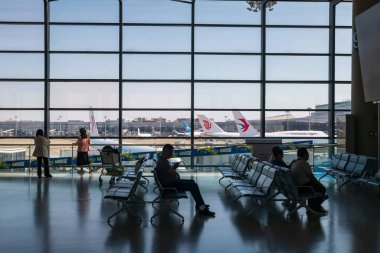 Yolcular Hongqiao Uluslararası Havalimanı 'nın kalkış terminali kapısında pist içinde birçok uçakla bekliyorlar..