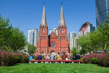 Arka Çinliler bahçe meydanı manzaralı St. Ignatius Xujiahui Katedrali 'nde mavi gökyüzüne, Şangay, Çin' e karşı otururlar. Baharda Şangay Piskoposu 'nun katedralinin ve yerinin ünlü seyahat yeri..