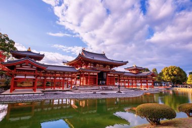 Kızıl Anka Salonu Byodo-In Tapınağı sonbaharda akçaağaç yaprağı renkleri ve ufuk çizgisi yansıması ile, Uji, Kyoto, Japonya. Aralık ayında Kansai 'de turistler için ünlü bir tatil beldesi.