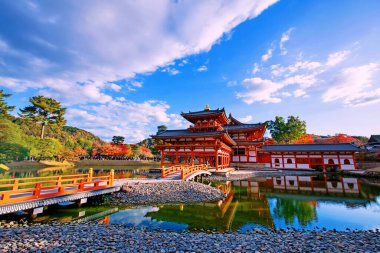 Sonbaharda renkli akçaağaç yaprakları ve ufuk çizgisi yansımasıyla Phoenix Byodo-In Tapınağı, Uji, Kyoto, Japonya. Aralık ayında Kansai 'de turistler için ünlü bir tatil beldesi.