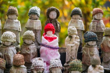 Hase-dera ya da Hasedera Tapınağı 'nda sonbaharda, Sakurai, Nara, Japonya' da kırmızı örgü şapkalı ve kolyeli Jizu heykelleri. Aralık 'ta Kansai' de turist turizminin son durağı.