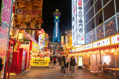  İnsanlar Tsutenkaku Kulesi 'nin Shinsekai Osakas Yeni Dünya restoranını, hediyelik eşya dükkanını ve gece hayatını ziyaret ediyor. Aydınlatılmış reklam panosuyla ünlü bir seyahat yeri.