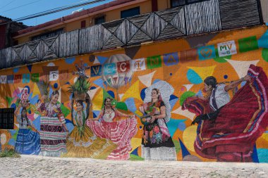 OAXACA, OAXACA, MEXICO-ECTOBER 31 Ekim 2024: Duvarda, Oaxaca, Meksika 'nın farklı bölgelerinden geleneksel kıyafetleri olan kadınlarla boyanmış resimler