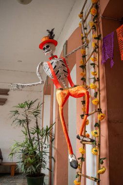 OAXACA, OAXACA, MEXICO - 31 Ekim 2024: Oaxaca, Meksika 'da Ölüler Günü kutlamaları için turuncu pantolon ve şapka giymiş iskelet
