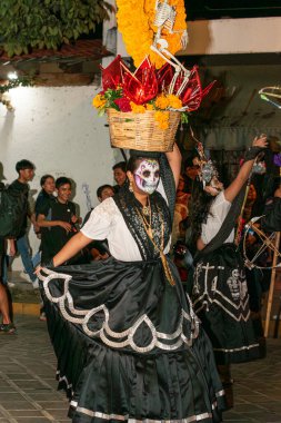 OAXACA, OAXACA, MEXICO-NOVEMBER 1, 2024: Oaxaca, Meksika 'da Ölüler Günü geçit töreninde kadın kafatası şeklinde boyanmış ve geleneksel giysiler giyip dans ediyordu