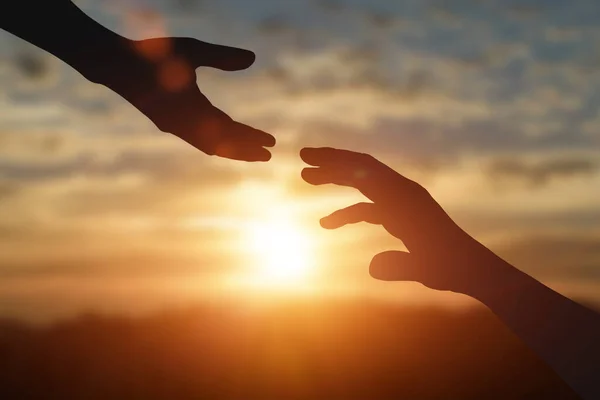 Uzanmanın silueti, yardım eli uzatmak, umut etmek ve gün batımında birbirinize destek olmak. Yardım, dostluk uluslararası gün konsepti.
