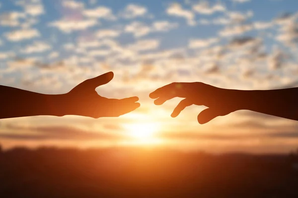 stock image Silhouette of reaching, giving a helping hand, hope and support each other over sunset background. Help, friendship international day concept.