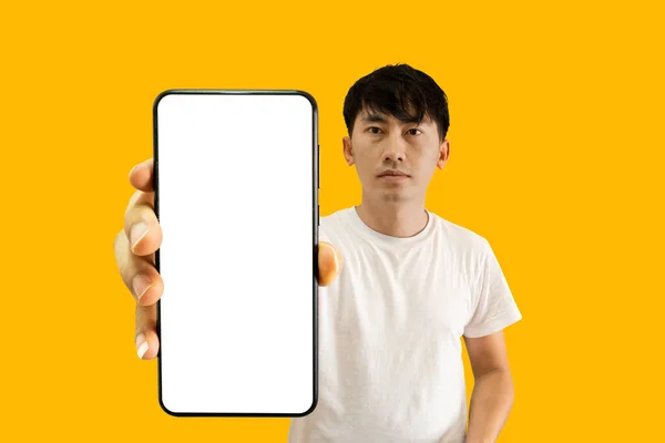 アジアの男は黄色の背景に白い空の画面でスマートフォンを保持 携帯電話の表示 モバイルアプリ広告のためのモックアップ — ストック写真