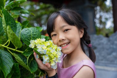 Çocuk bahar günü ortanca çiçeğinin tadını çıkarıyor..