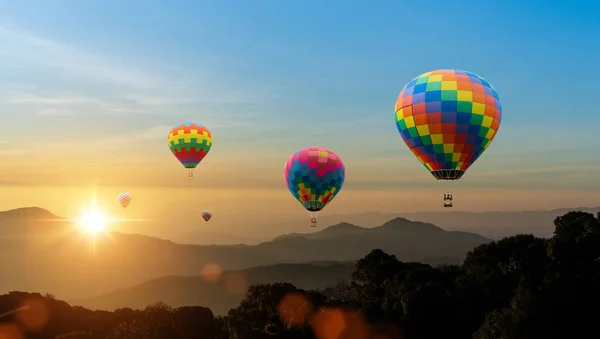 日の出の空を背景に山の上を飛ぶカラフルな熱気球 自然の背景を旅する — ストック写真