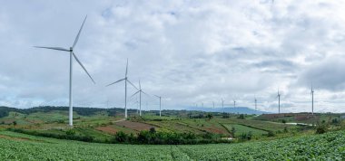 Tarım alanlarında bulutlu gökyüzü olan panorama rüzgar türbinlerinin manzarası. Yenilenebilir dostane enerji kavramı