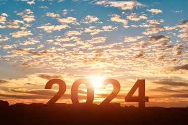 Mutlu yıllar 2024 gün batımında ya da gündoğumunda atlayan kadın silueti.