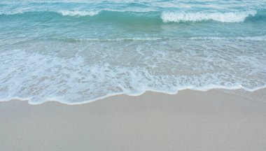 Kumlu sahilde yumuşak bir mavi okyanus dalgası. Adaya yaz tatili. berrak gök mavisi arka plan.