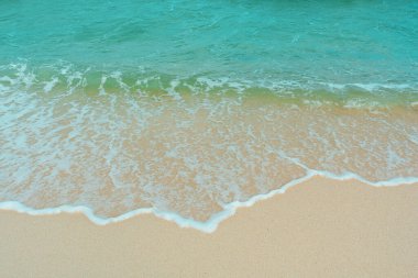 Kumlu sahilde yumuşak bir mavi okyanus dalgası. Adaya yaz tatili. berrak gök mavisi arka plan.