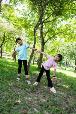 Parkta gülümseyen iki mutlu kız çocuğu. Çocuklar yeşil parkta oynuyor ve yaz gününün tadını çıkarıyor..