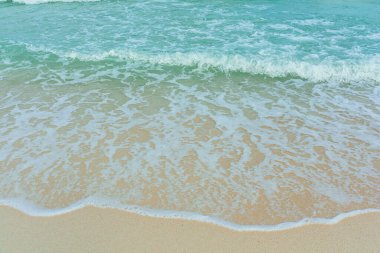 Kumlu sahilde yumuşak bir mavi okyanus dalgası. Adaya yaz tatili. berrak gök mavisi arka plan.