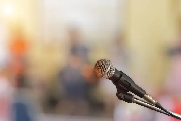 Close-up of microphone on stage for speaker speech with blur bokeh light background.