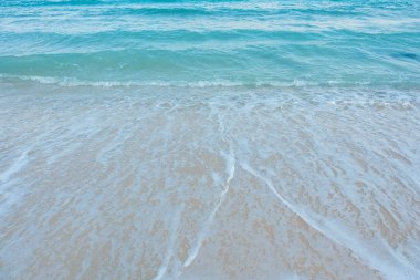 Kumlu sahilde yumuşak bir mavi okyanus dalgası. Adaya yaz tatili. berrak gök mavisi arka plan.