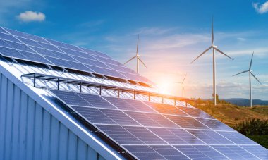 Mavi gökyüzü zemininin altında güneş panelleri ve rüzgar türbinleri.