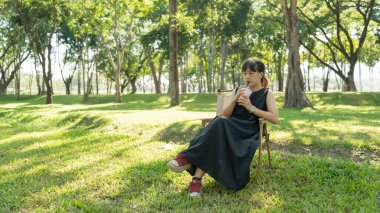 Kamp sandalyesinde oturan çocuk parkta içki içiyor..