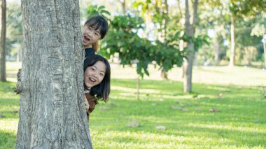 İki kız kardeş parktaki ağacın arkasından bizi gözetliyor.