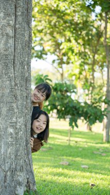 İki kız kardeş parktaki ağacın arkasından bizi gözetliyor.
