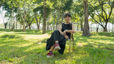 Çocuk yeşil parktaki kamp sandalyesinde dinleniyor..