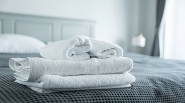 Yatak odasında, yatak odasına kıvrılmış beyaz havlu yakın plan, rahat konsept hisset.