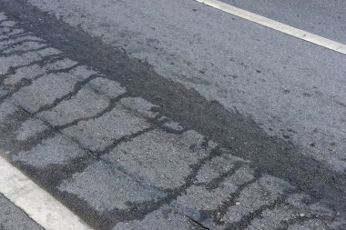 Çizik ve çatlaklarla asfalt yol yüzeyi.