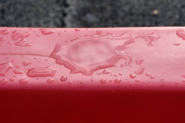 Kırmızı metal yüzeye su damlaları