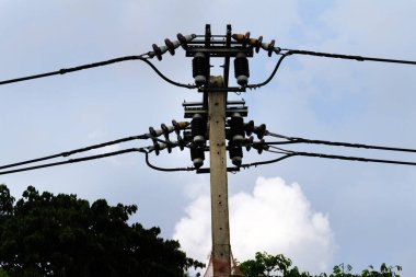 Mavi arka planda kabloları olan elektrik direği