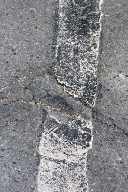 Asfalt yol yüzeyinde çatlaklar ve çizikler var.