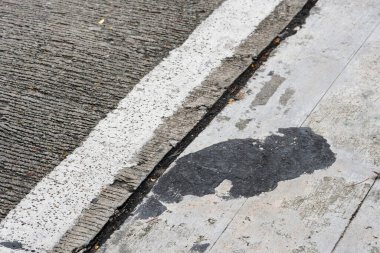 Kaldırımda gri ve siyah çizgiler olan asfalt yol