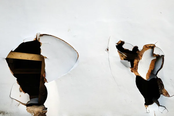 Eski beyaz bir duvarın arka planında kırık ve kırık bir pencere var..