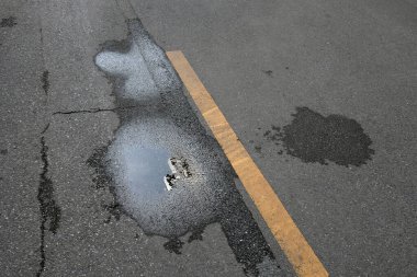 Sokakta bir delik olan asfalt yol.