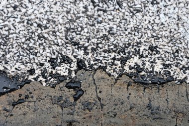 Siyah ve beyaz asfalt yolda bir sürü çatlak ve çizik var.