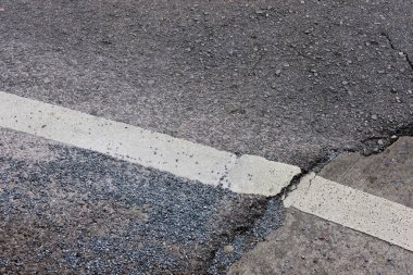 Yol yüzeyinde kırık çatlaklar ve çizikler var.