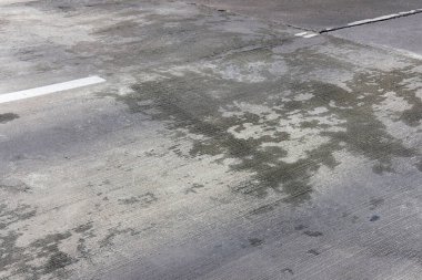 Kirli asfalt yol yüzeyinde çatlaklar ve çizikler var.