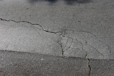 Çatlak asfalt yolda çatlaklar, çatlaklar ve çizikler.