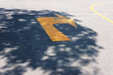 Parktaki asfalt yolda sarı boyalı yol tabelası