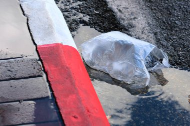 Beyaz lastik eldivenli yol tabelası ıslak bir kaldırımda yatıyor.