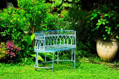 Yeşil çimlerin üzerinde dekoratif metal sandalye.