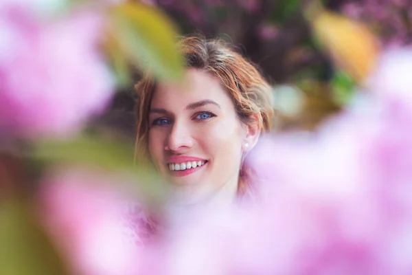 Young happy Caucasian woman between cherry blossom portrait at springtime