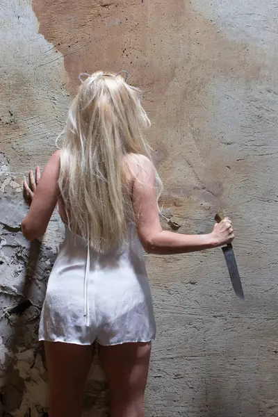 夜色中的金发女人拿着锋利的刀架在墙上 复仇的念头 — 图库照片#