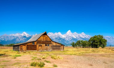 ABD 'nin Wyoming eyaletinde Mormon Row Tarihi Bölgesi' nde T. A. Moulton Barn ile Grand Teton Ulusal Parkı 'nın ikonik manzarası.