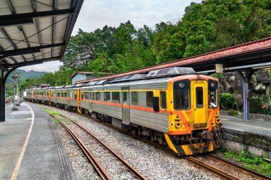 Yerel yolcu treni, New Taipei, Tayvan 'ın yemyeşil tepelerine kurulmuş Shifen İstasyonu platformunda bekliyor. Manzaralı istasyon tarihi Pingxi Hattı 'nın bir parçası olup, turistler tarafından büyüleyici kırsal manzarası ve gökyüzü feneriyle tanınıyor.