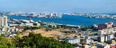 Shoushan 'da görülen Kaohsiung Limanı' nın panoramik manzarasında yoğun liman tesisleri, demirli gemiler, endüstriyel vinçler ve tarihi Hamasen tren yolu tersanesi yer alıyor. Şehir manzarası sahil boyunca uzanır, binalar ve altyapı ile.